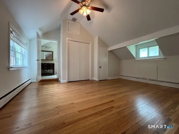 an empty room with wooden floor chandelier fan and windows