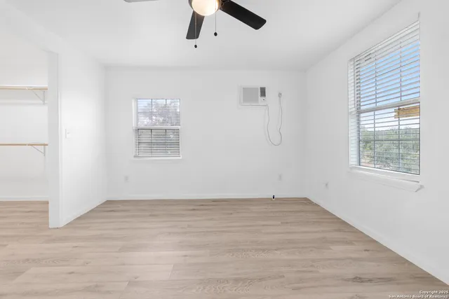 a view of an empty room with window and a ceiling fan