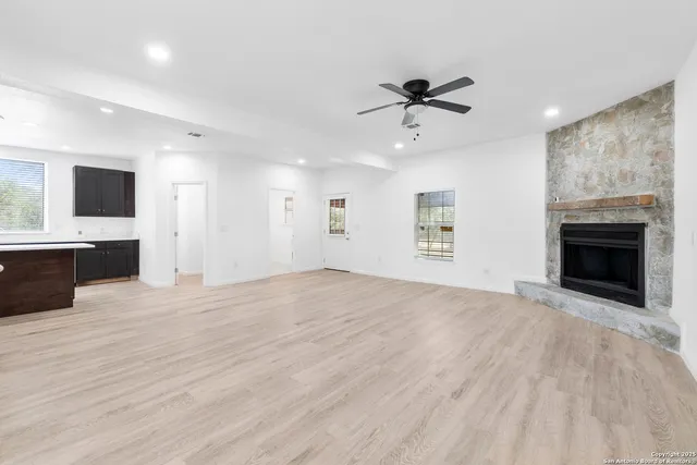 an empty room with wooden floor fireplace and windows