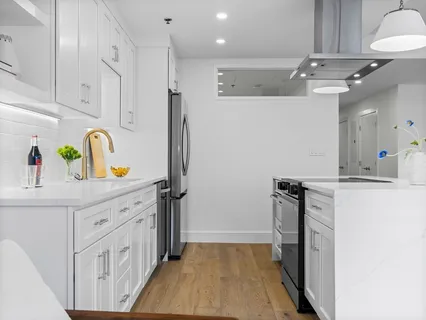 a kitchen with a refrigerator a sink and wooden floor