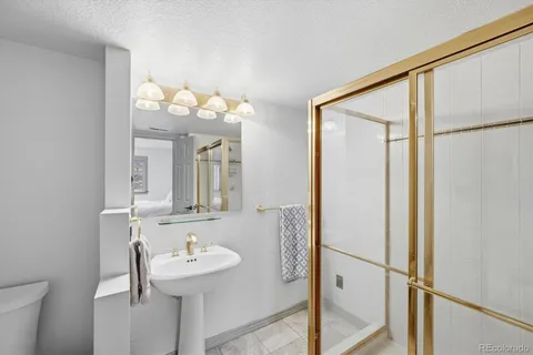 a bathroom with a granite countertop toilet a sink a mirror a shower curtain