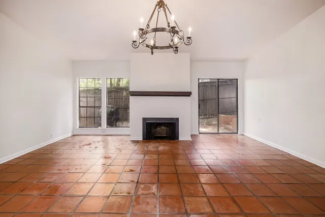 a view of a livingroom with a fireplace a chandelier and windows