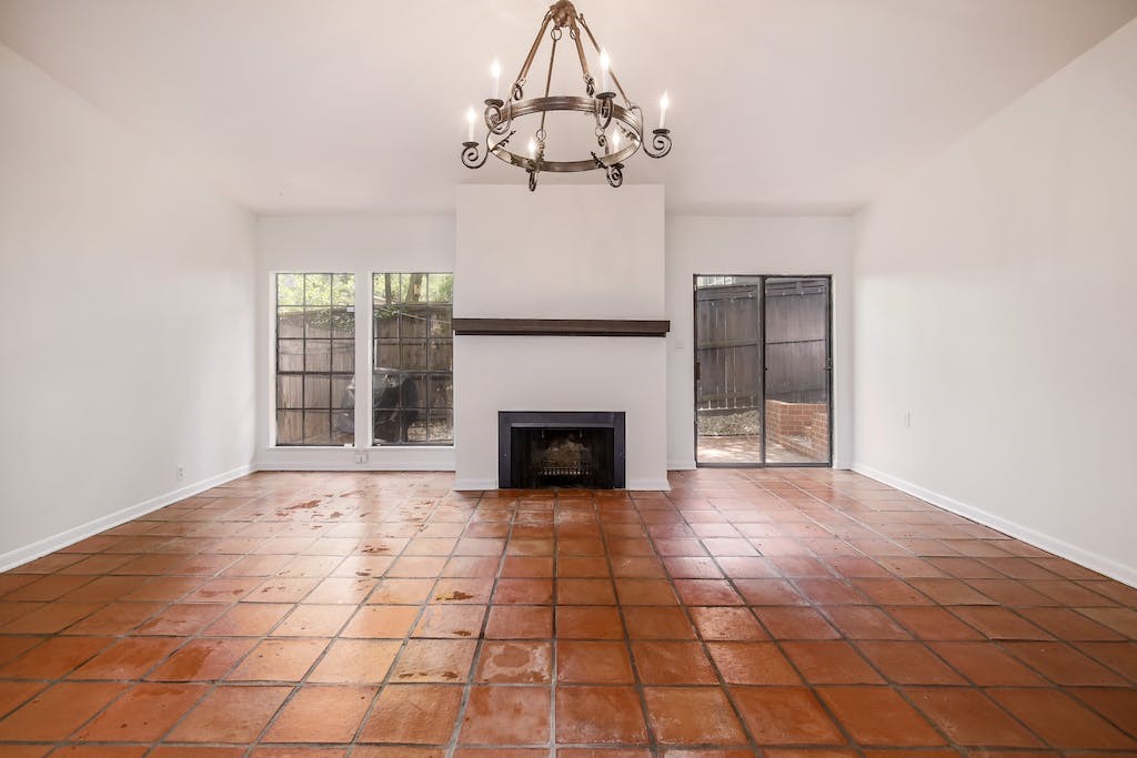 a view of a livingroom with a fireplace a chandelier and windows