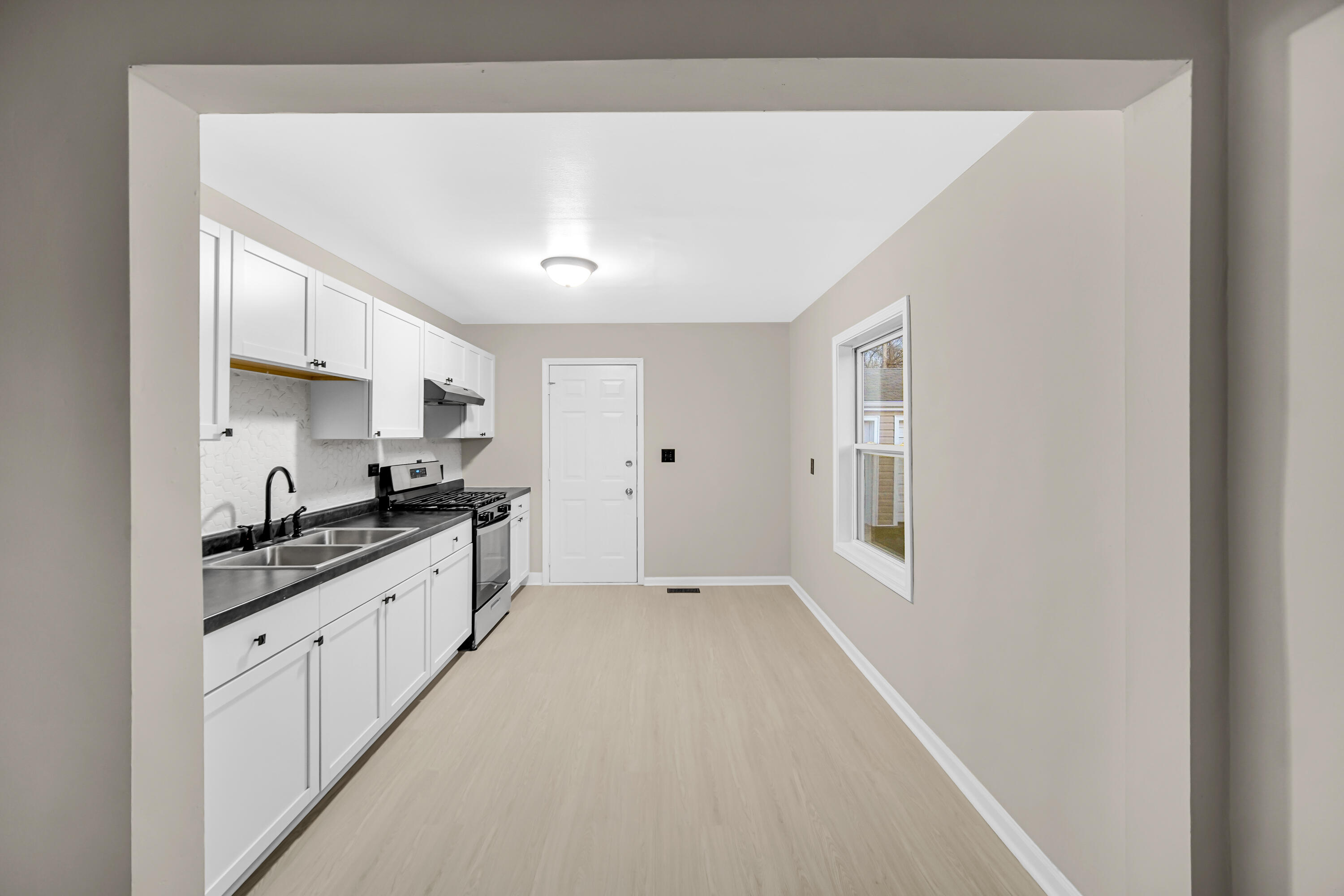 625 South Wells Street Gary, IN 46403 - Photo 7 of 18 a large white kitchen with granite countertop a lot of counter space and wooden floor