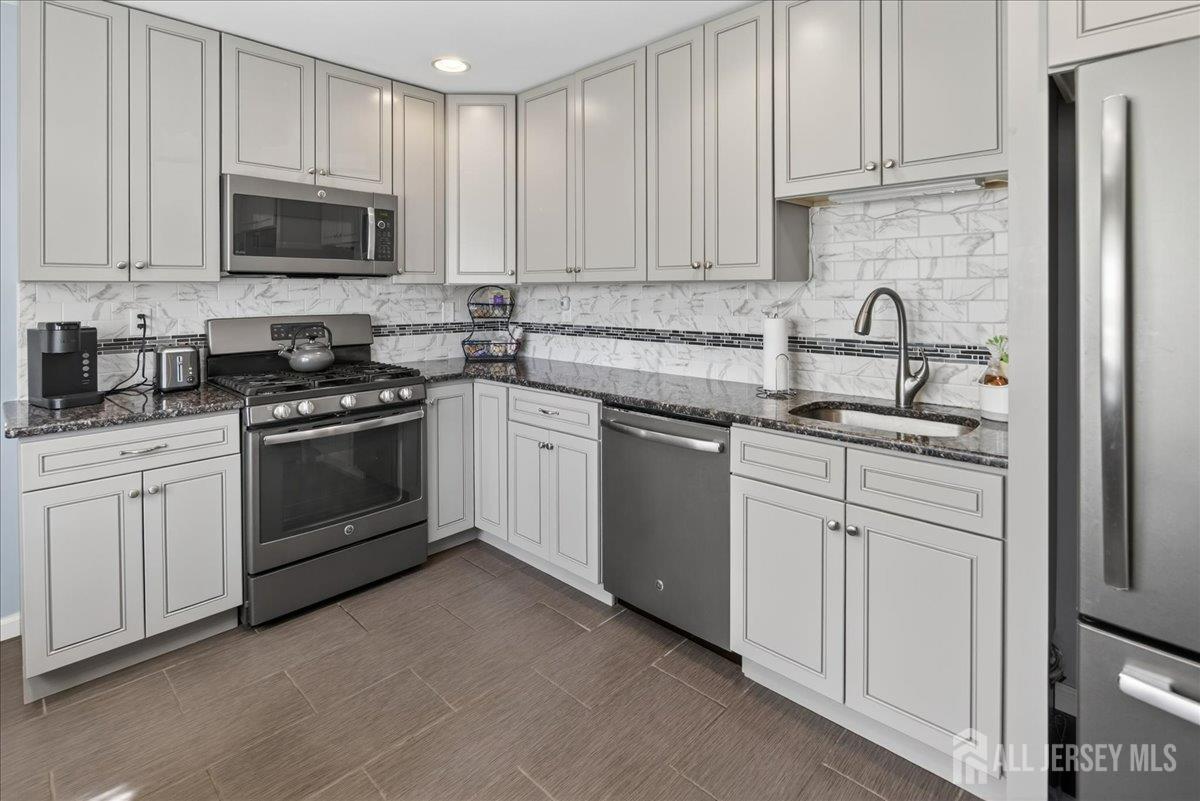 13 Comstock Road Edison, NJ 08817 - Photo 6 of 22 a kitchen with white cabinets and stainless steel appliances