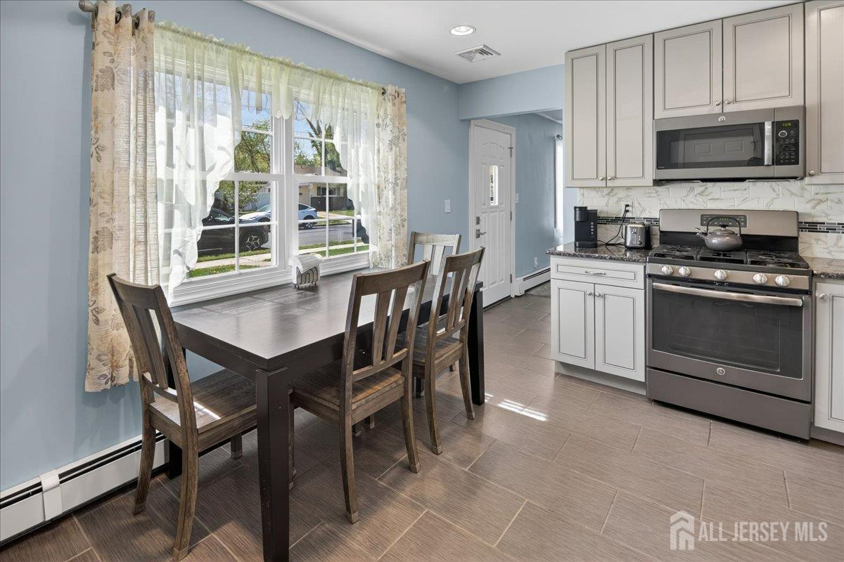 13 Comstock Road Edison, NJ 08817 - Photo 8 of 22 a kitchen with stainless steel appliances a stove a sink a microwave a dining table and chairs