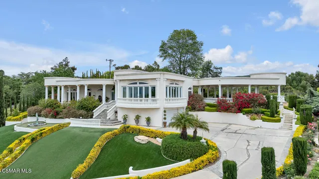 a front view of a house with a garden and trees