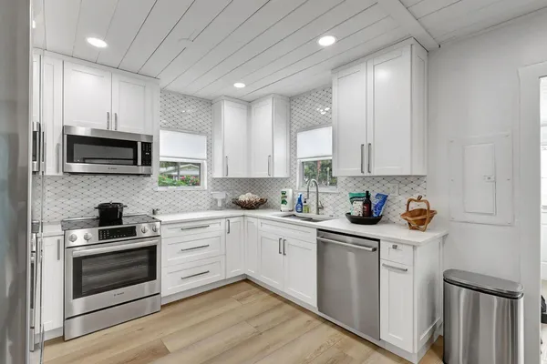 a kitchen with stainless steel appliances granite countertop a stove a sink and a microwave