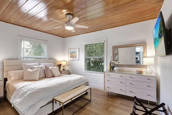 a bedroom with a large bed and a flat tv screen on dresser