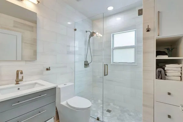 a bathroom with a shower a sink a toilet and mirror