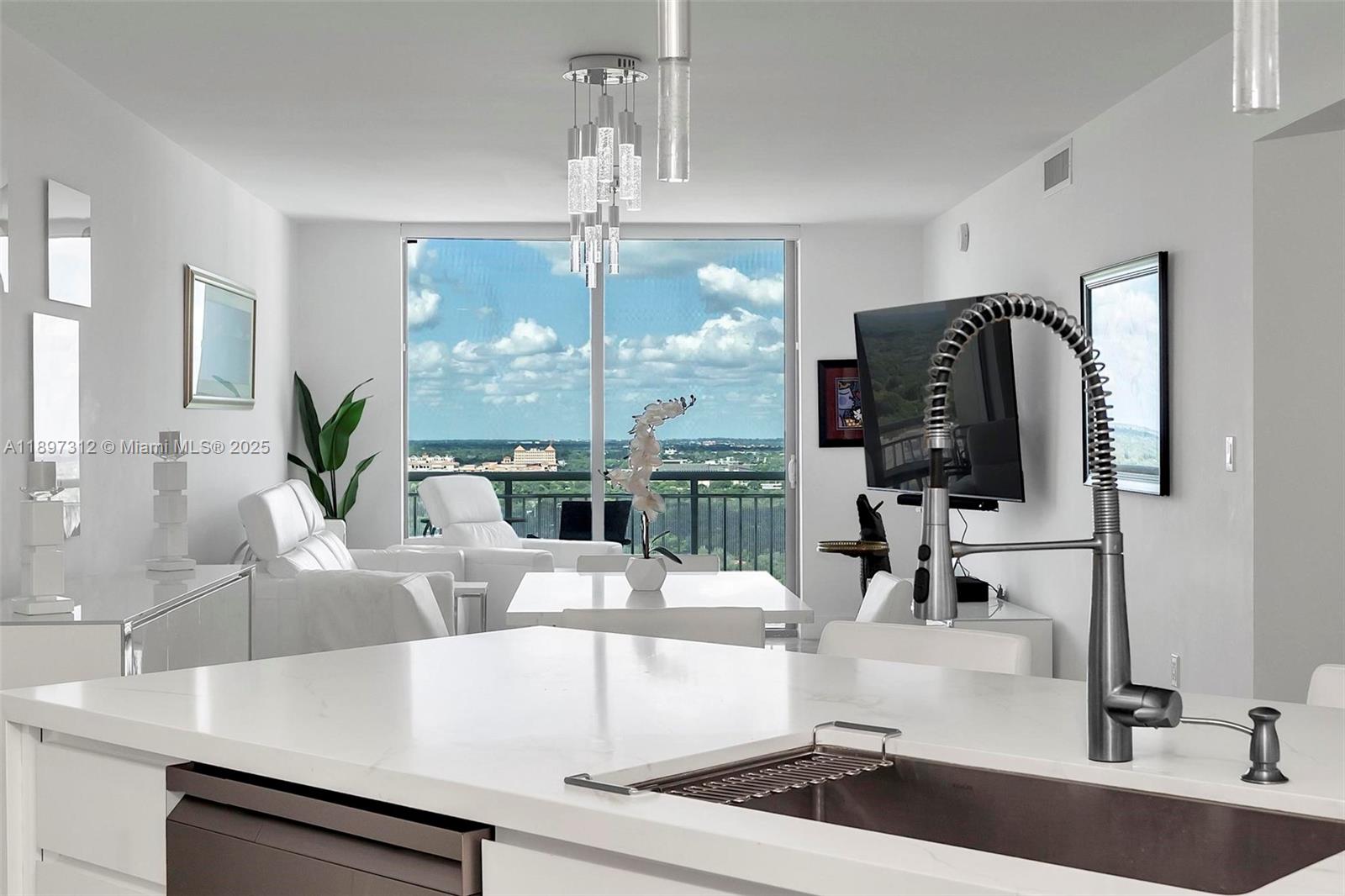9066 Southwest 73rd Court, Unit 2110 Miami, FL 33156 - Photo 12 of 45 a kitchen with a faucet a chandelier and living room view