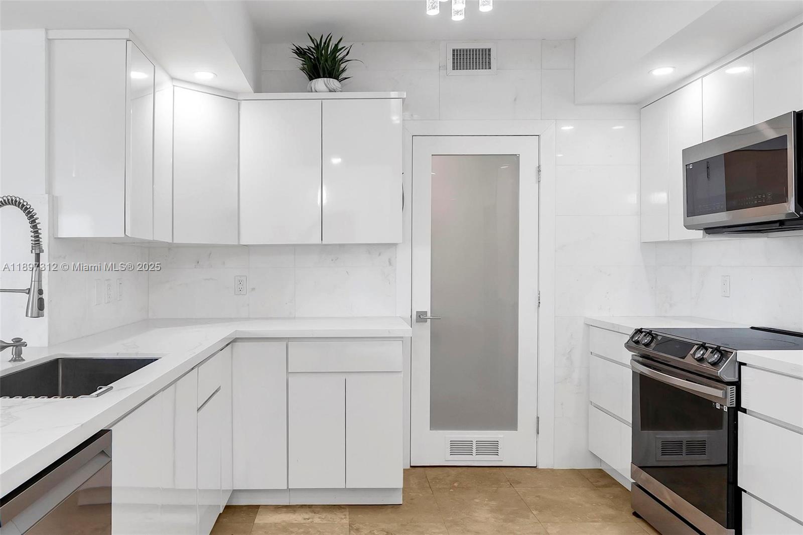 9066 Southwest 73rd Court, Unit 2110 Miami, FL 33156 - Photo 9 of 45 a kitchen with white cabinets and stainless steel appliances