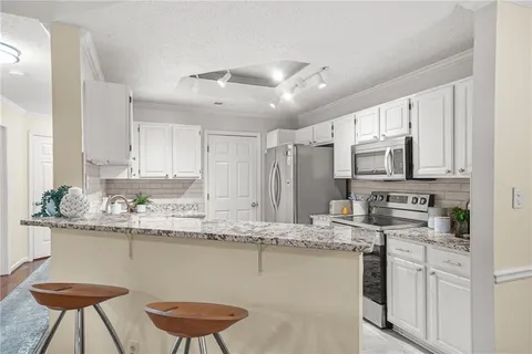 a kitchen with stainless steel appliances granite countertop a kitchen island a stove a sink a dining table and chairs