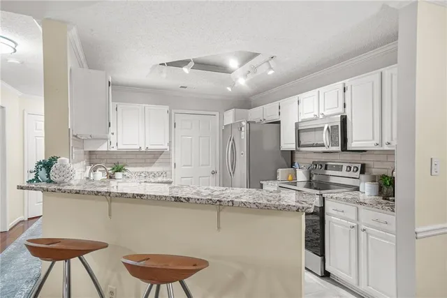 a kitchen with stainless steel appliances granite countertop a kitchen island a stove a sink a dining table and chairs