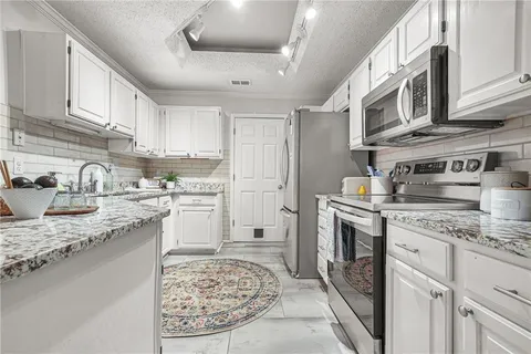 a kitchen with stainless steel appliances granite countertop a sink a stove and cabinets