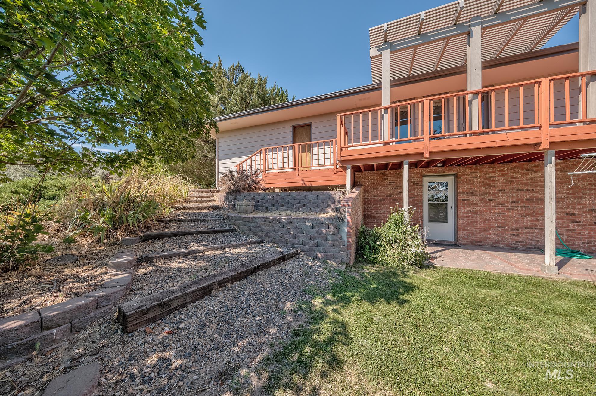 1493 Cove Road Weiser, ID 83672 - Photo 40 of 50 Terraced landscaping featuring retaining walls and gravel steps leading to a wooden deck with railing