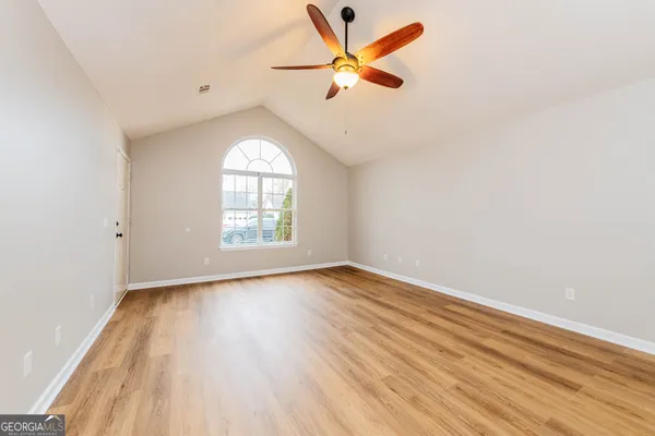 an empty room with wooden floor fan and windows
