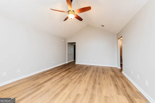 an empty room with wooden floor ceiling fan and windows