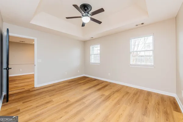 a view of empty room with wooden floor and fan