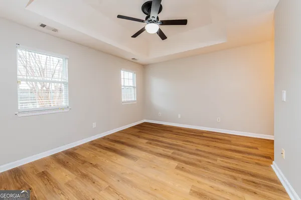 a view of empty room with wooden floor and fan