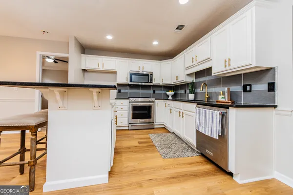 a kitchen with kitchen island granite countertop a sink a counter top space stainless steel appliances and cabinets