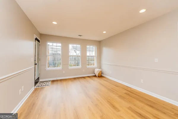 a view of an empty room with a window and wooden floor