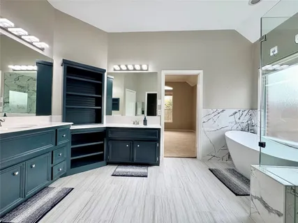 a spacious bathroom with a tub double sink and mirror