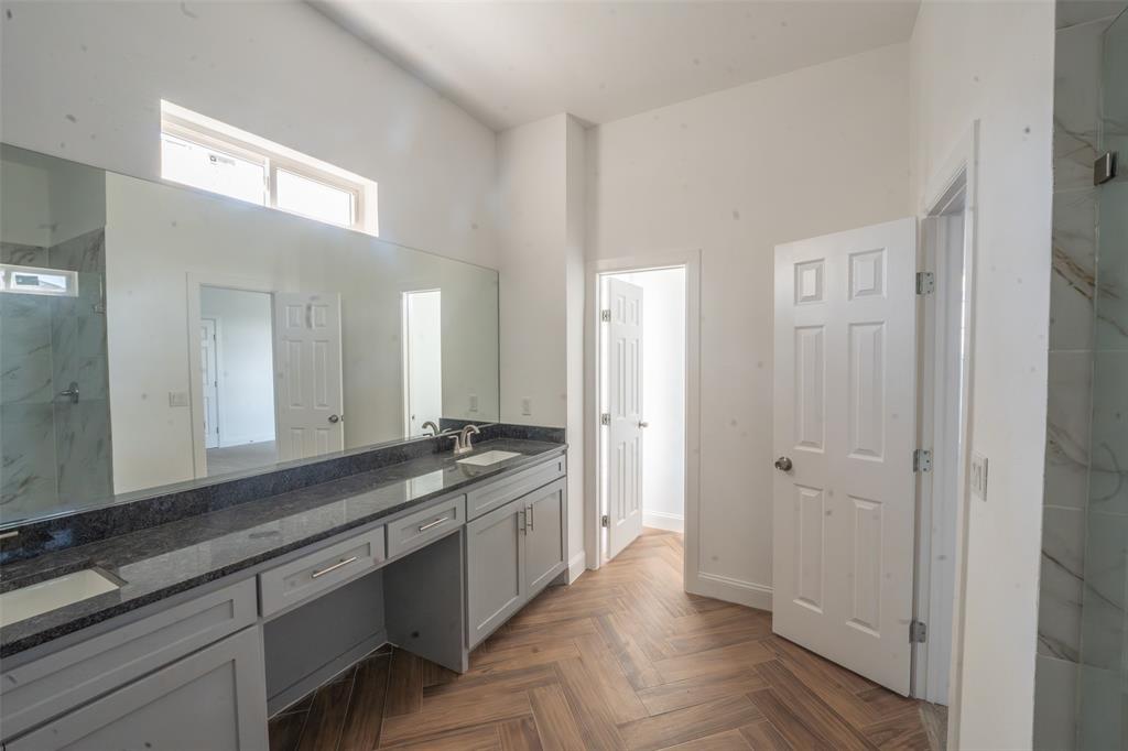1408 Spinnaker Lane Azle, TX 76020 - Photo 4 of 8 Herringbone wood-finish flooring complements the spacious bathroom featuring a dual vanity with a dark countertop and light gray cabinetry