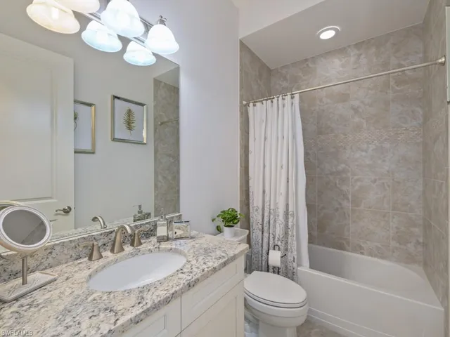a bathroom with a granite countertop sink a toilet and bathtub