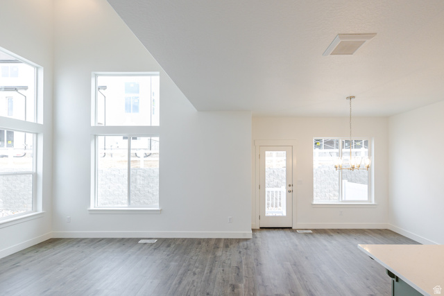 4741 Olive Avenue, Unit 406 Mapleton, UT 84664 - Photo 10 of 20 Unfurnished dining area with light wood finished floors, suspended lighting, and a high ceiling