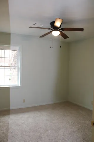 an empty room with a window and chandelier fan