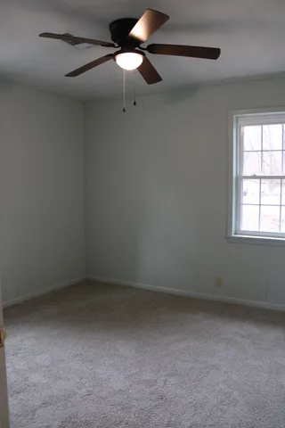 an empty room with a window and a fan
