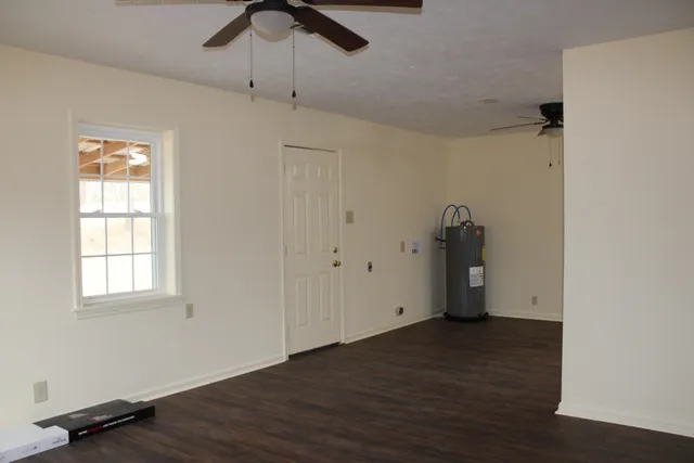 an empty room with wooden floor cabinet and windows