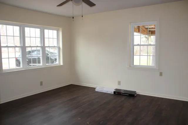 an empty room with wooden floor and windows