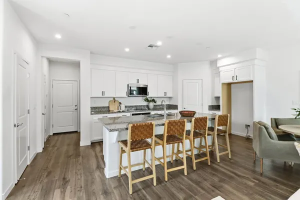 a view of a dining room with furniture wooden floor and a view of kitchen