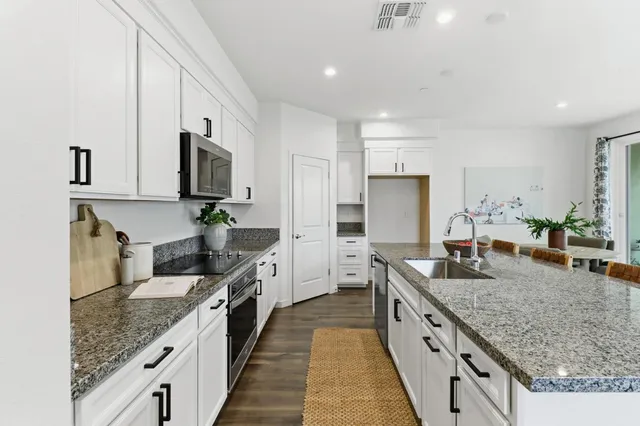 a large kitchen with kitchen island granite countertop a sink and dishwasher a stove with wooden floor