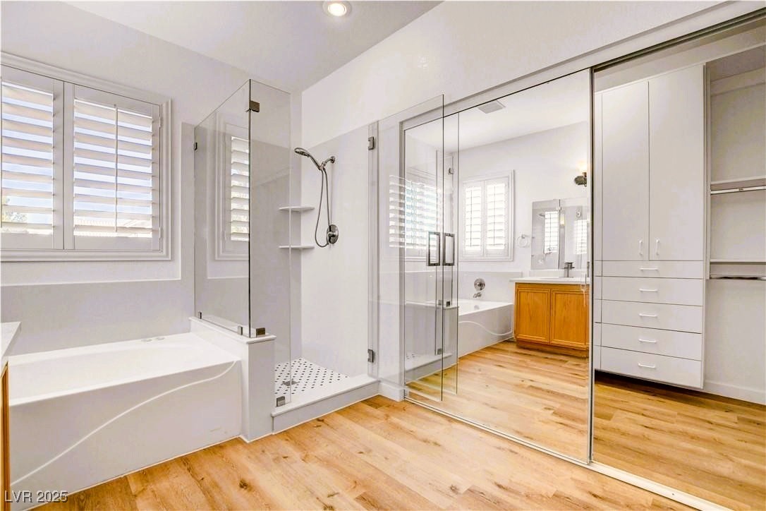 10247 Splendor Ridge Avenue Las Vegas, NV 89135 - Photo 12 of 38 Full bath featuring a bath, vanity, a shower stall, and light wood-type flooring