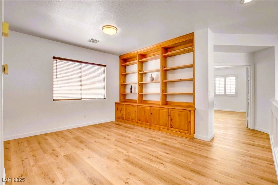 10247 Splendor Ridge Avenue Las Vegas, NV 89135 - Photo 7 of 38 Empty room featuring light wood-type flooring, a textured ceiling, and built in features