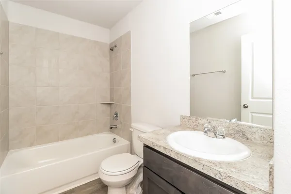 a bathroom with a granite countertop sink a toilet and a bathtub