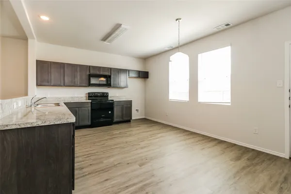 a kitchen with stainless steel appliances granite countertop a sink a stove top oven a counter space and cabinets