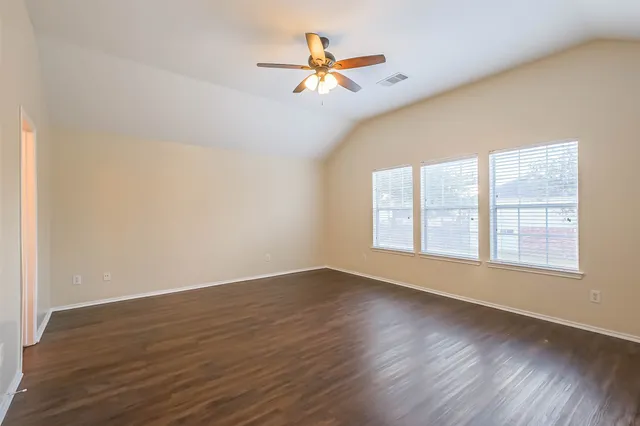 an empty room with wooden floor and windows