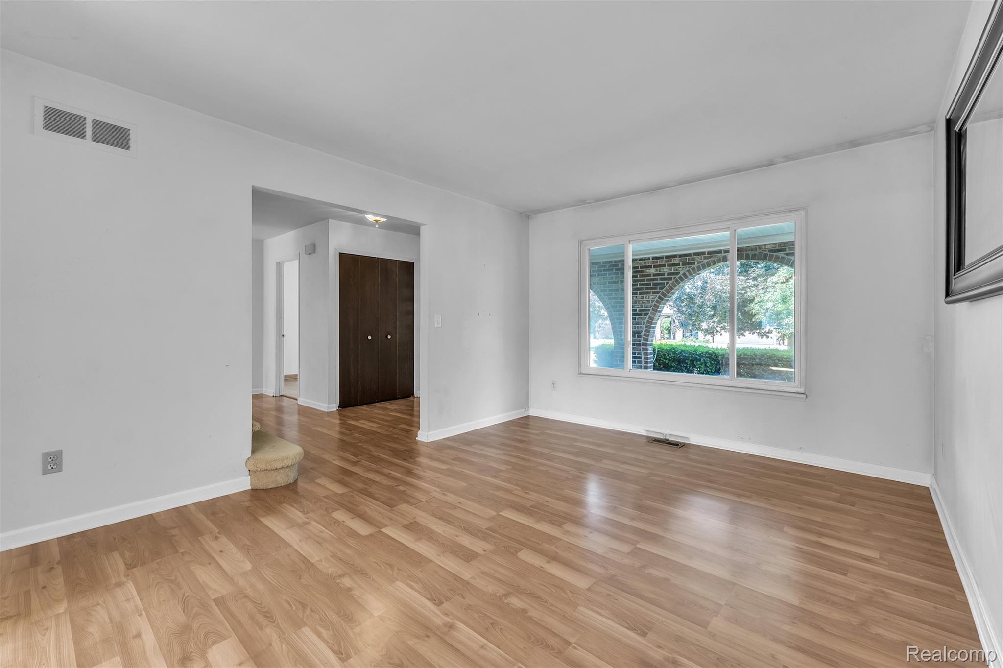 7000 Woonsocket Street Canton, MI 48187 - Photo 8 of 65 Bright living area featuring wood-finish flooring, a large window with brick archway details, and white baseboards