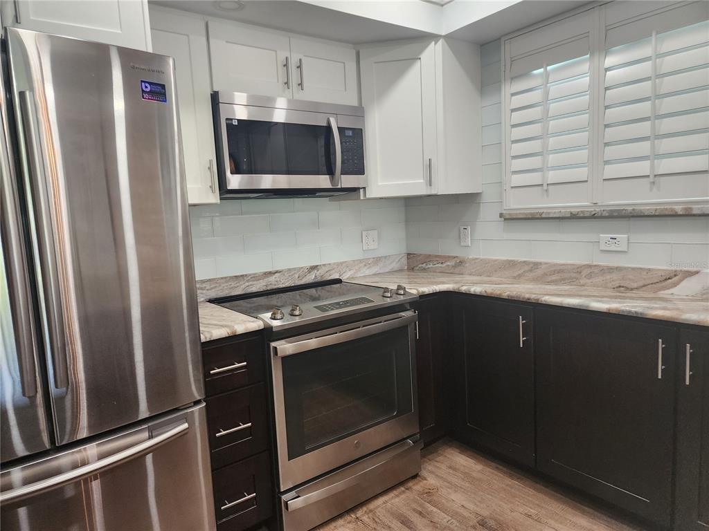 802 Hidden Harbour Drive Indian Rocks Beach, FL 33785 - Photo 9 of 31 a kitchen with stainless steel appliances a stove a microwave and a sink