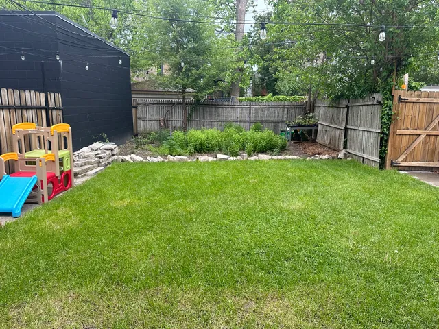 a backyard of a house with table and chairs plants and large tree