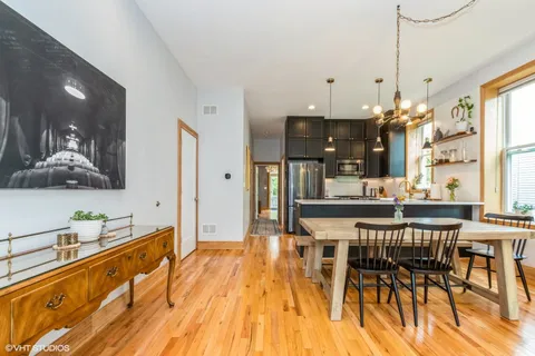 a dining hall with stainless steel appliances kitchen island granite countertop a table and chairs in it