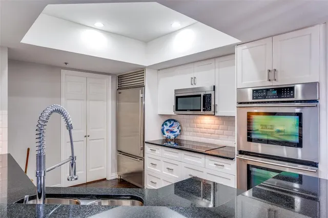 a kitchen with stainless steel appliances white cabinets a stove and a sink