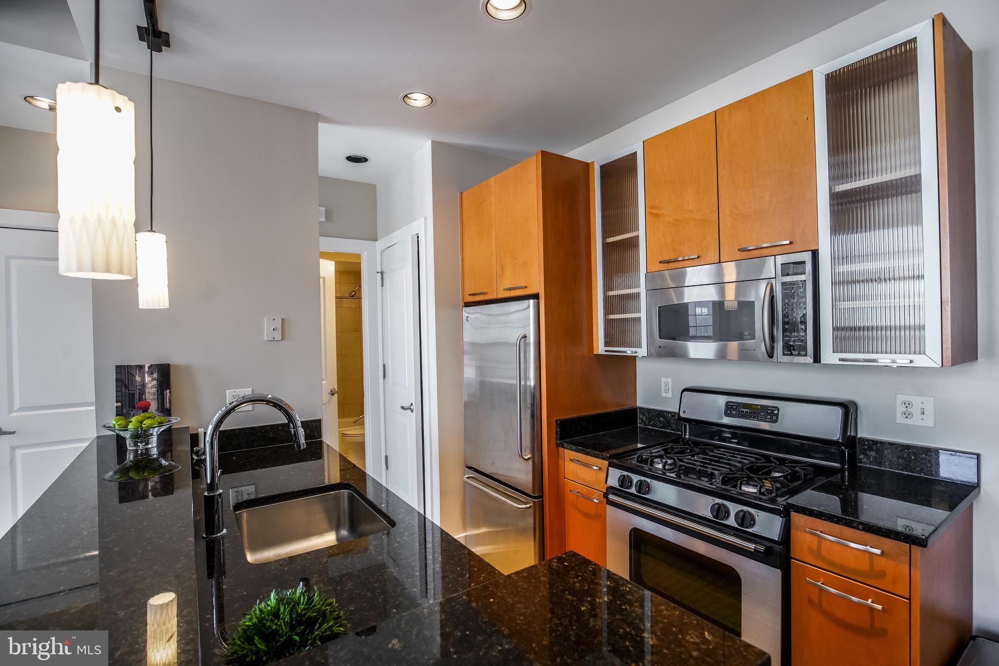 2421 18th Street Northwest, Unit 302 Washington, DC 20009 - Photo 5 of 30 a kitchen with stainless steel appliances granite countertop a stove and a refrigerator