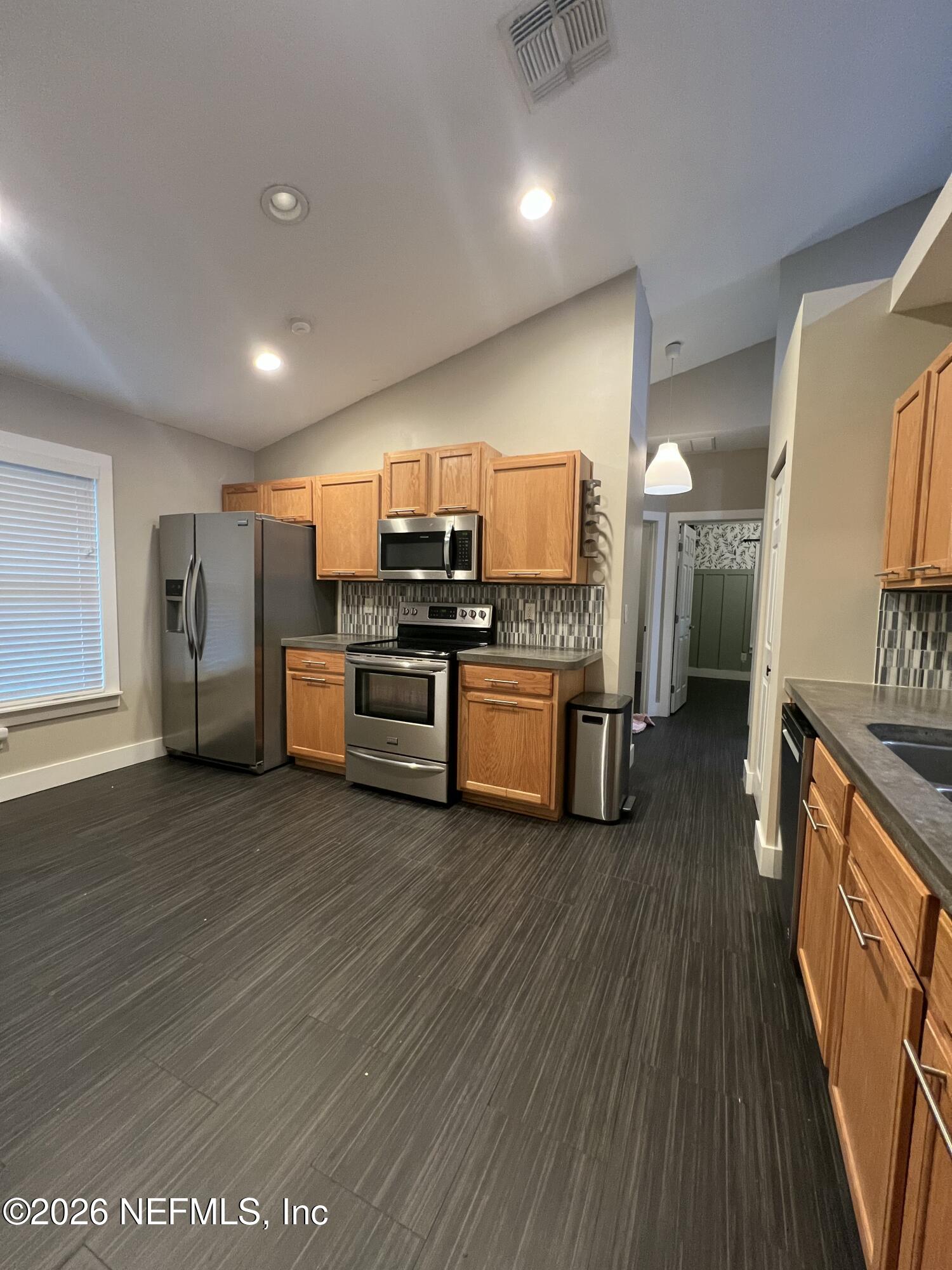 1115 Main Street Atlantic Beach, FL 32233 - Photo 5 of 14 a kitchen with stainless steel appliances wooden floors and wooden cabinets