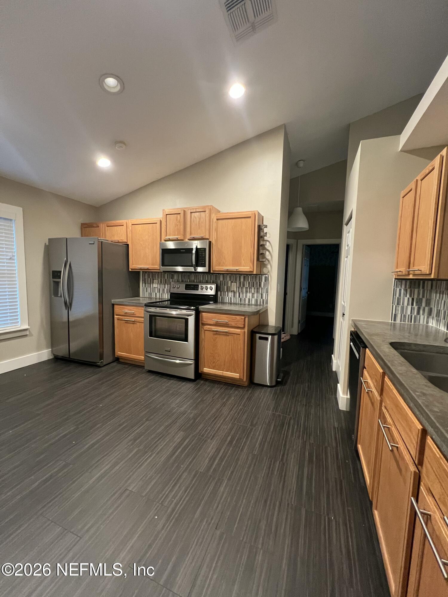 1115 Main Street Atlantic Beach, FL 32233 - Photo 6 of 14 a kitchen with stainless steel appliances wooden floors and wooden cabinets