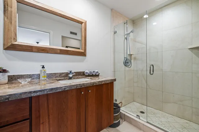 a bathroom with a granite countertop sink toilet mirror and shower